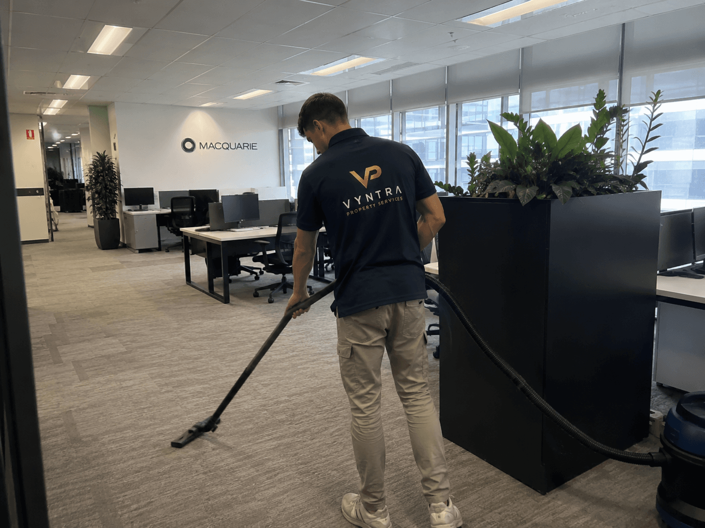 A Vyntra cleaning professional vacuuming an open-plan corporate office