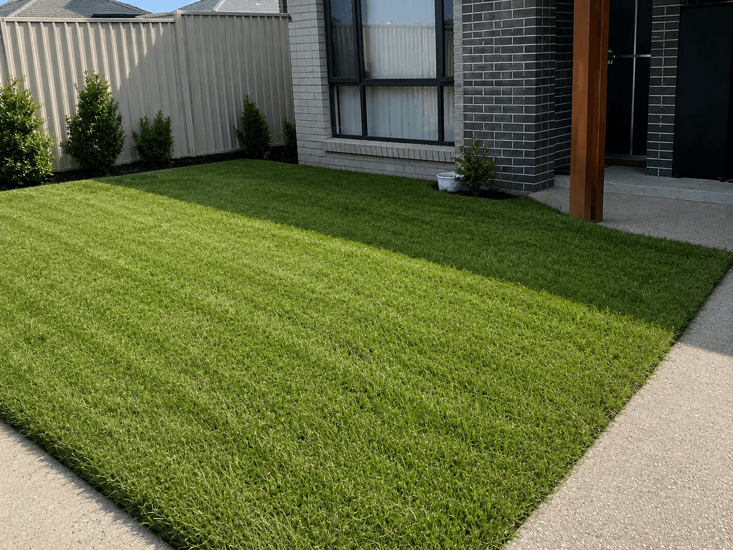 An overgrown front lawn transformed into a neat, manicured green lawn, after